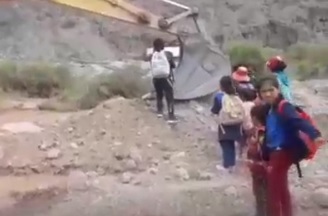 Para ir a la escuela, los chicos deben atravesar un caudal de agua a bordo de una retroexcavadora