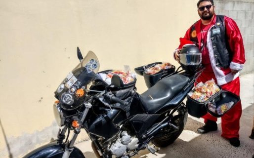 Un vecino se vistió de Papá Noel y salió en su moto a repartir golosinas a los niños del barrio